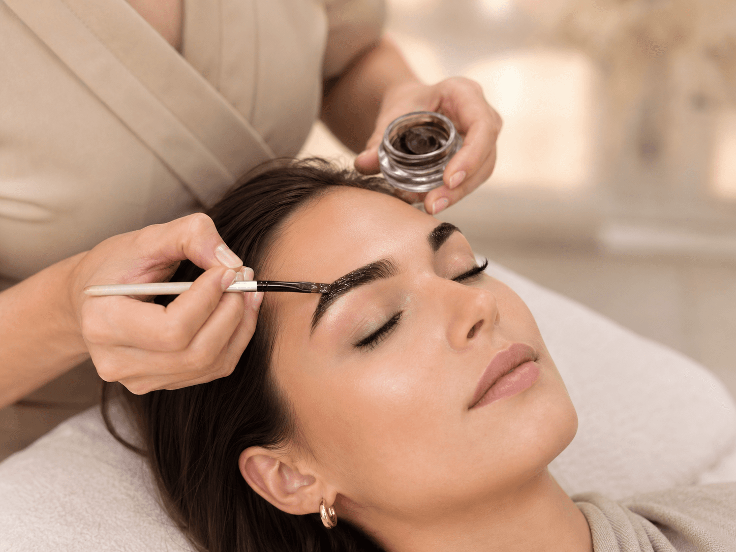 Brow tint treatment being applied in a soft studio setting.